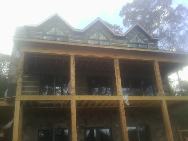 Dormers and porch framing on a large log home under construction — Roof Coating work by our crew in Indialantic