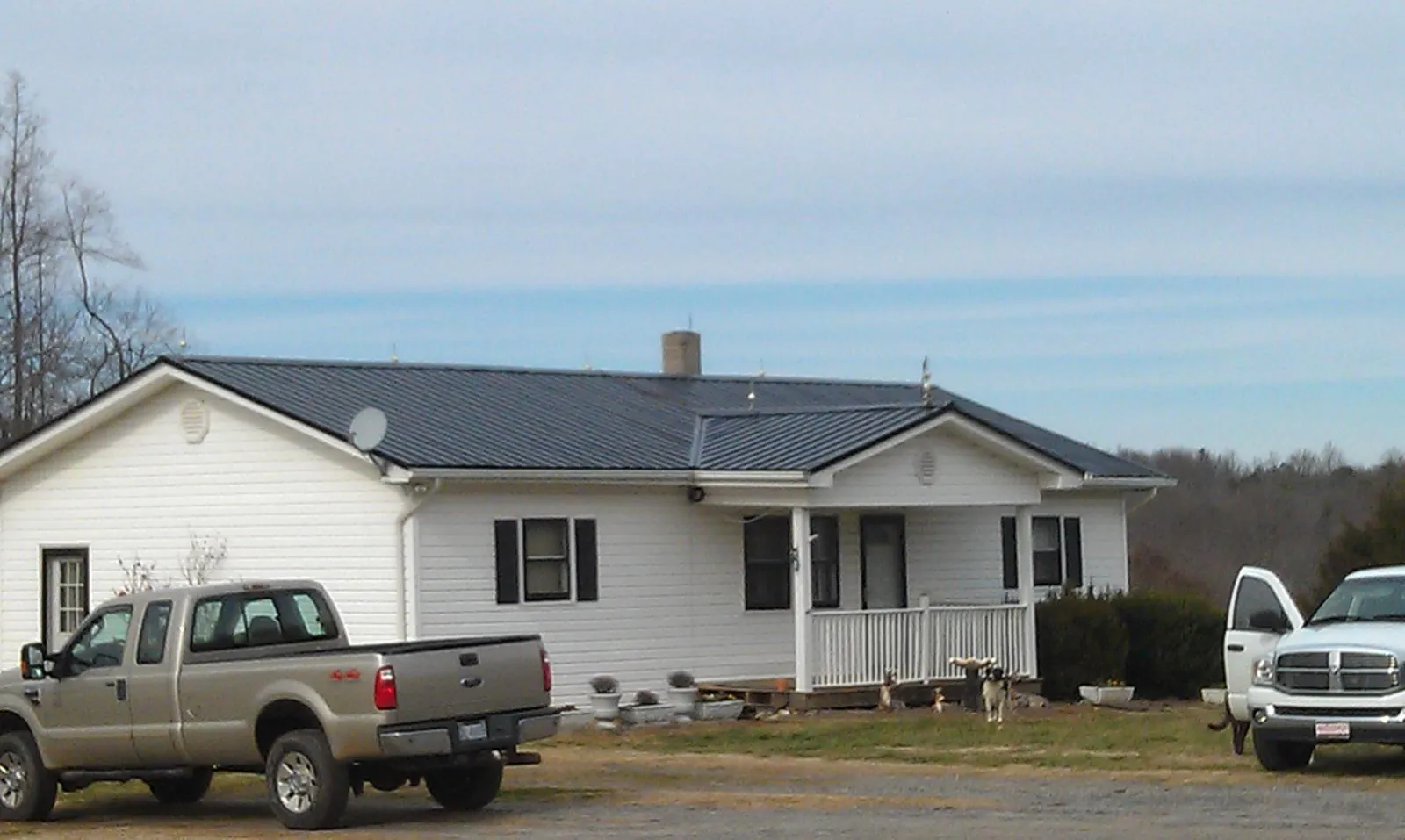 Finished dark metal roof on a white ranch home with work trucks parked in Indialantic